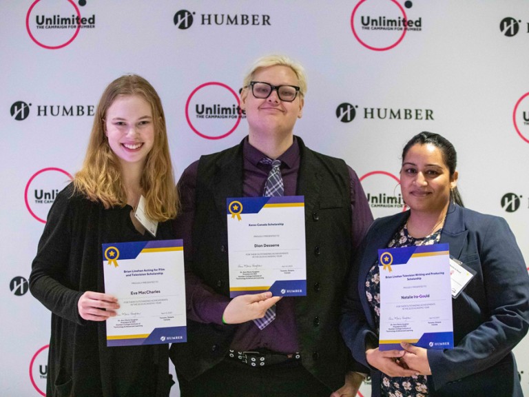 Three people hold their awards