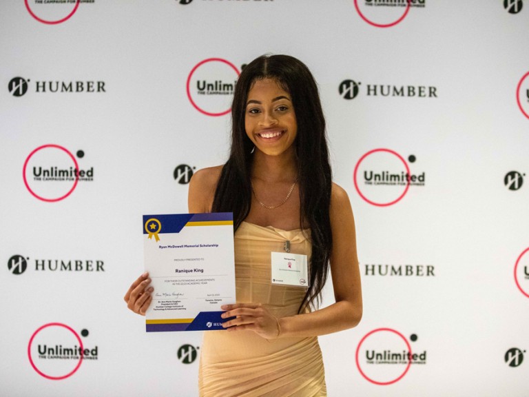 Person holds their award smiling for camera