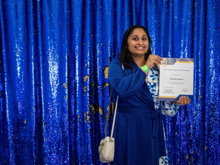 Person holding award in front of blue backdrop