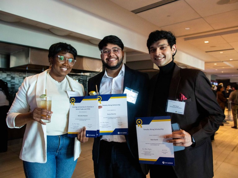 Three scholarship recipients take photo together holding their scholarship certificates
