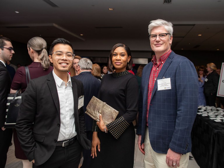 Three people pose for camera in event hall