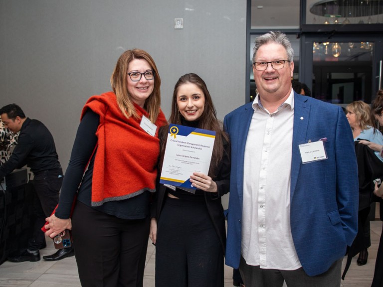 Scholarship recipient takes photo with two guests