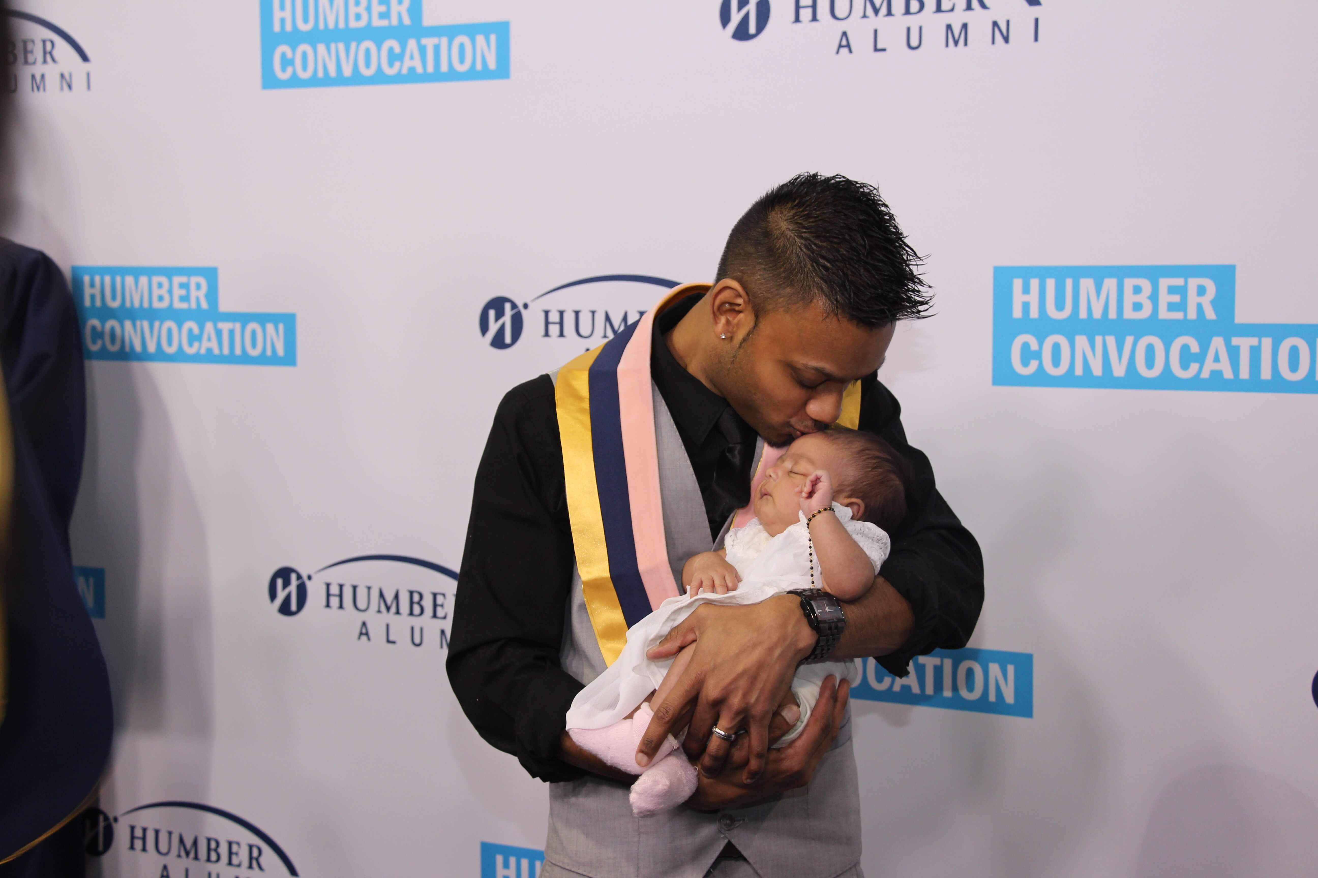 Student kissing his child while posing for after graduation pic