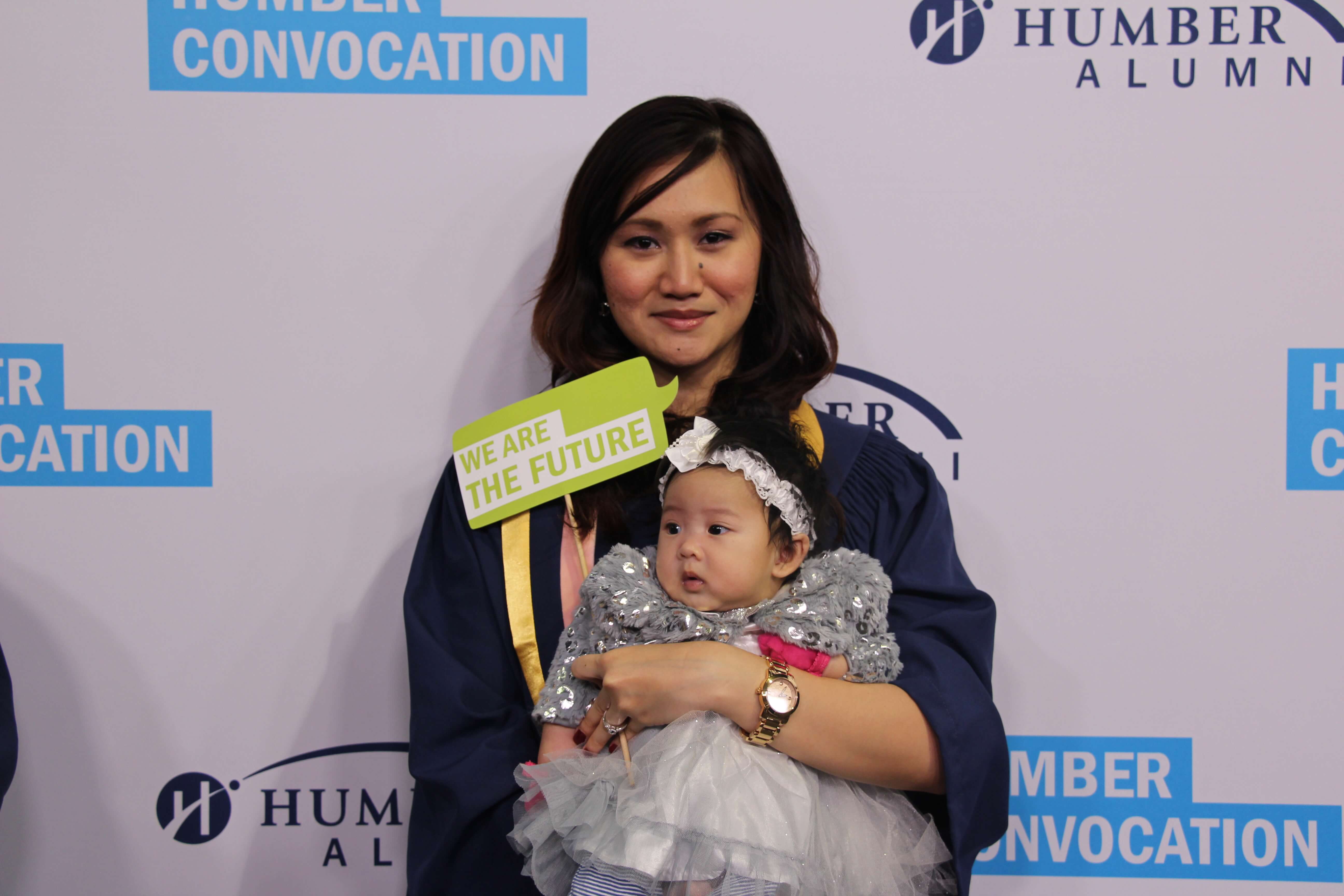 Student holding her babay while posing for after graduation pic