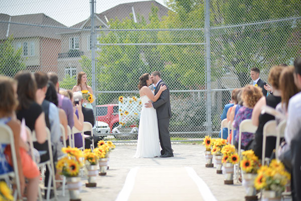 Matt and Andrea's wedding day, kissing at a baseball diamond