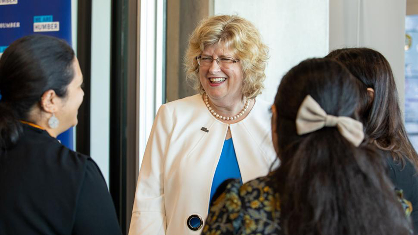 A smiling Dr. Ann Marie Vaughan speaks with a group of people.