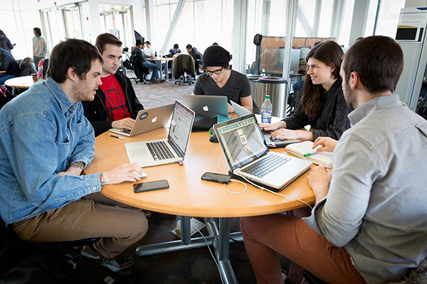 group of students working at a table on their laptops