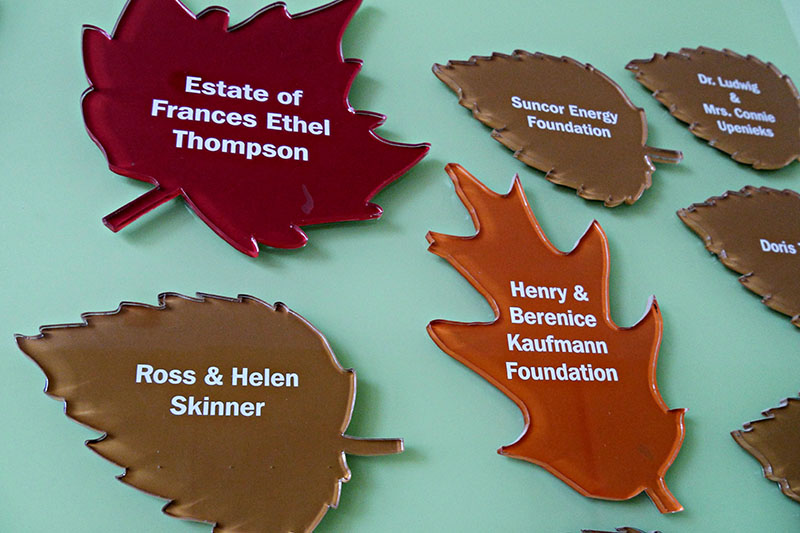 Leaf-shaped plaques on a wall bear the names of various past donors.
