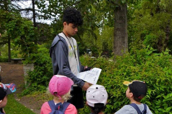 A teen explains an activity to a group of children outdoors