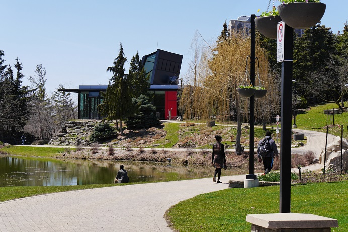 Students walk up a path toward a glass building with a red door