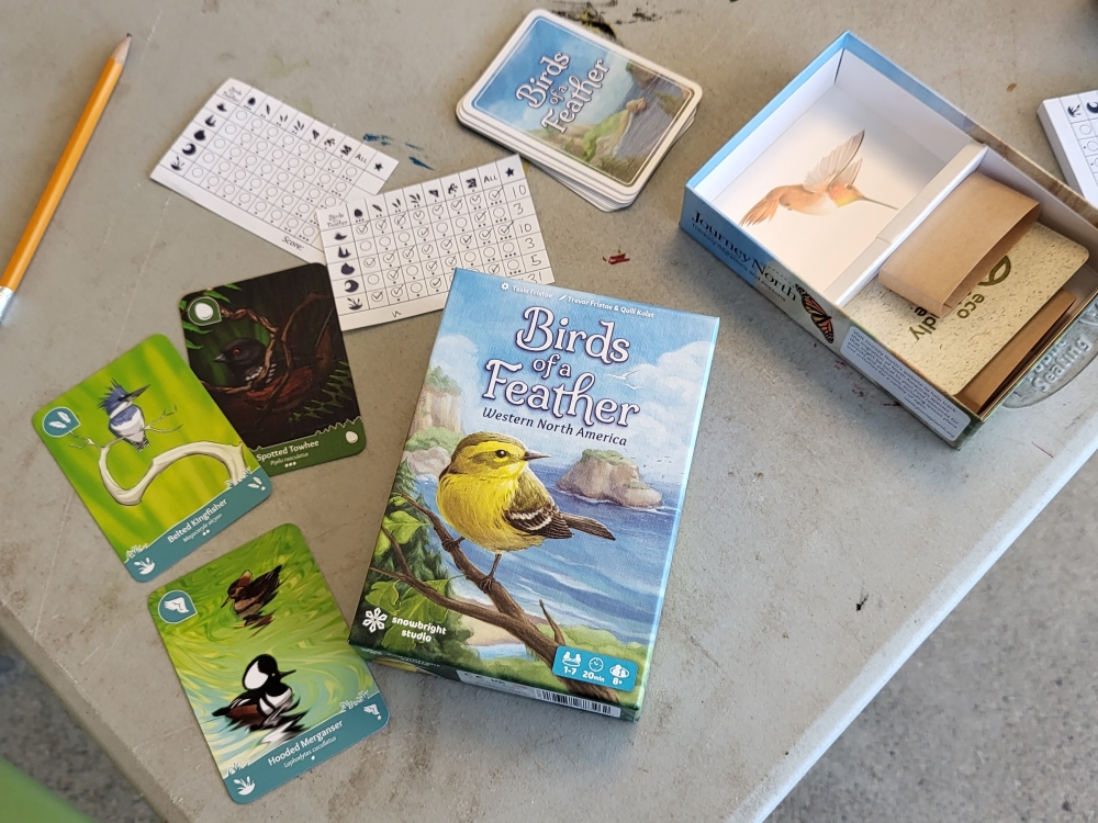 The game Birds of a Feather is open on a table, showing cards featuring images of birds and a scoresheet.