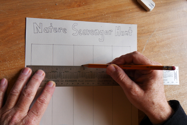 A man uses a ruler to draw a large grid on a piece of paper which has the words Nature Scavenger Hunt hand-printed at the top