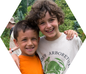 Two young boys with their arms around each other smile for the camera, one wearing a camp t-shirt.