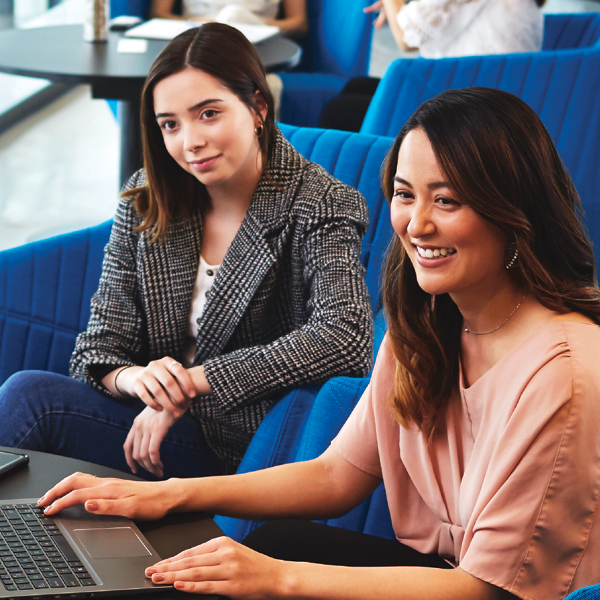 2 females sitting while one is working on a laptop