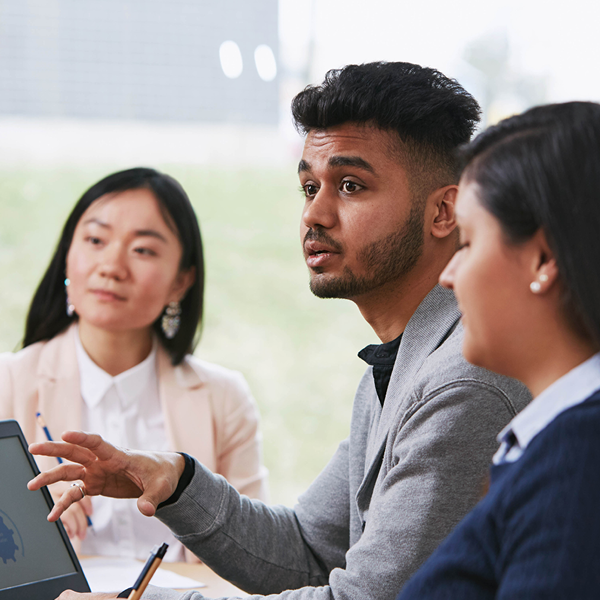 3 people sitting at desk in front of computer