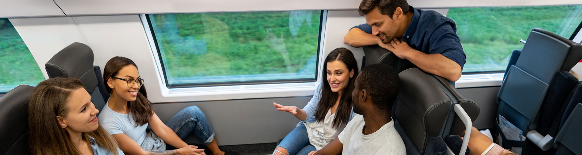 Group of young adult sitting on a train smiling