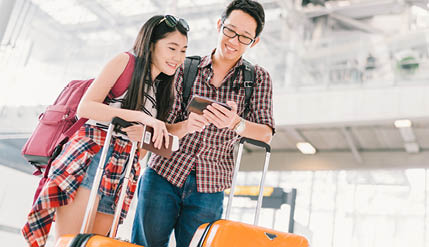 guy and girl standing with suitcases and looking at a phone