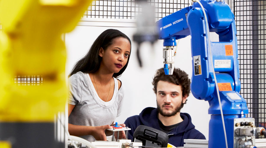 Two students operating mechanical robot arms