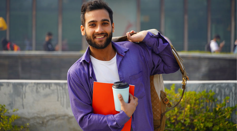 Person holding backpack over shoulder and smiling