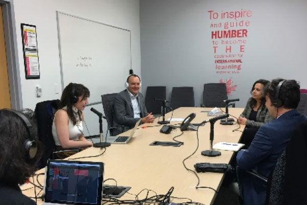 People around a table speaking into microphones for the podcast