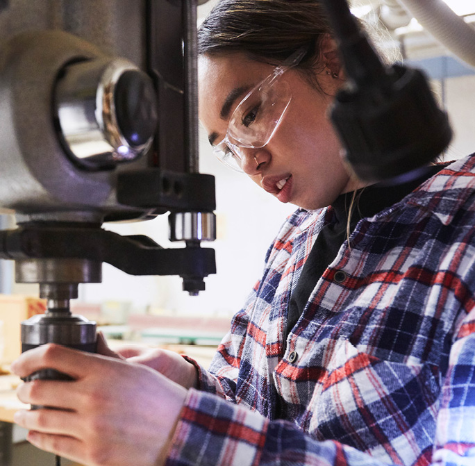 student wearing safety goggle using heavy machinery