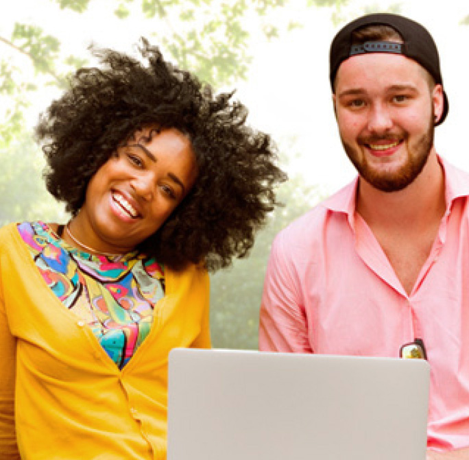 two smiling students with a laptop