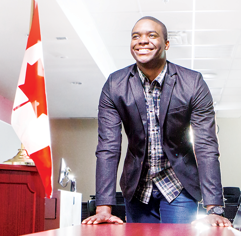 person standing in front of a desk with canadian flag beside it