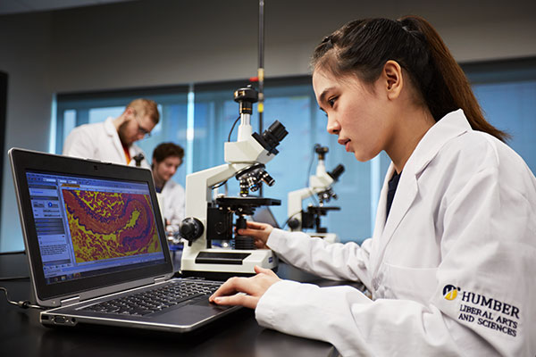 student using laptop wearing lab coat