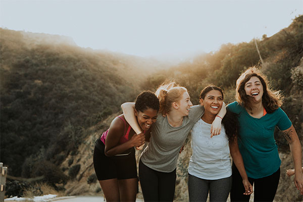 4 females standing with their arms around each others shoulders