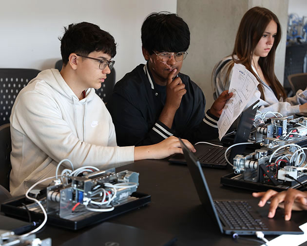 high school students deeply engaged in a collaborative robotics or engineering project.