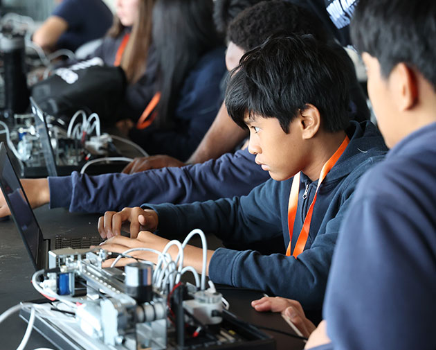 two students collaborating intently on a circuit or robotics interface on a laptop