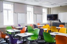 Orange, green, purple and yellow chairs at desk in a classroom