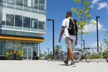Student walking towards the Humber Learning Resource Commons, bike racks on right