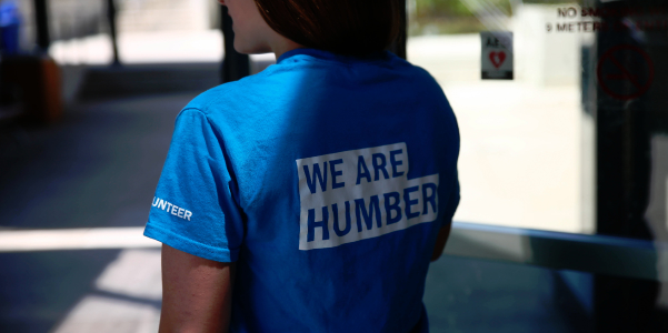 The back of a volenteer woman with a We Are Humber t-shirt