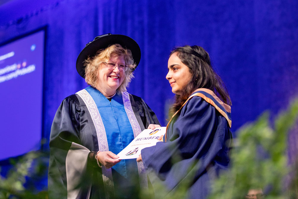 Ann Marie Vaughn presenting certificate to graduate on stage