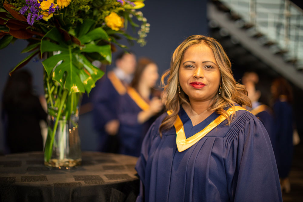 Grad posing in front of vase of flowers