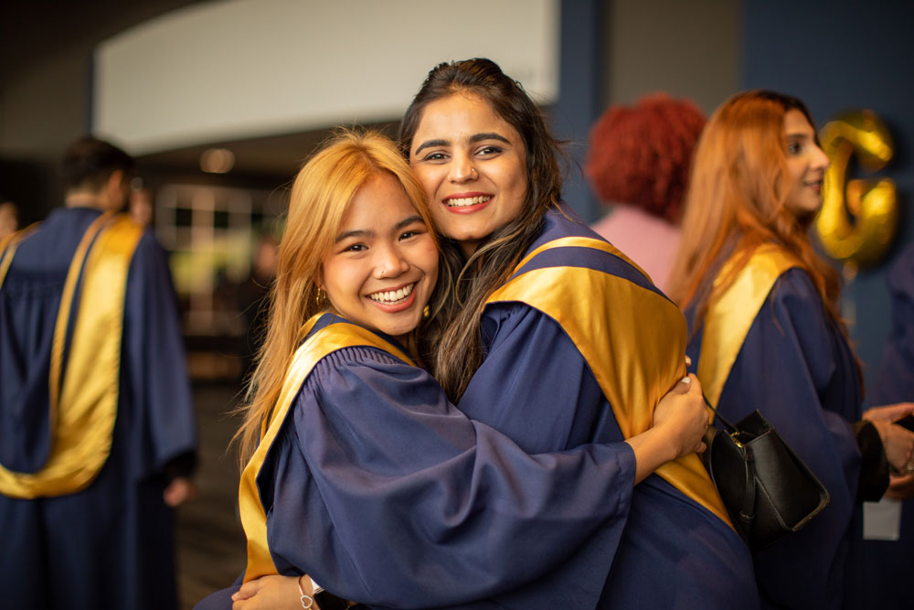 Two grads hugging each other