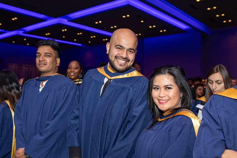 Graduates in ceremony hall smile for photo