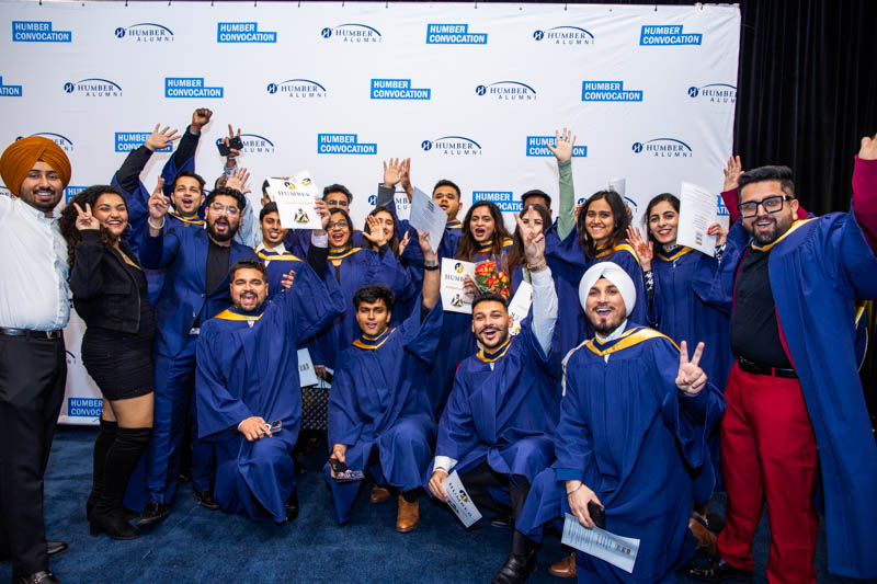 Large group of graduates raise their arms in celebration for photo
