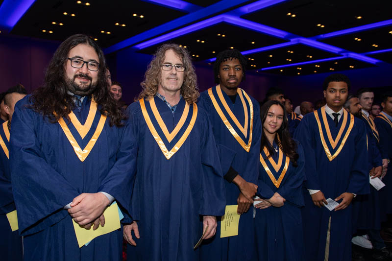 Row of graduates look at camera