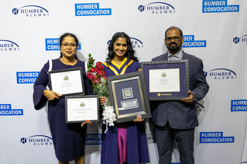 Graduate with parents holding framed awards