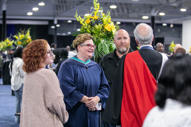 Graduate talking with three people