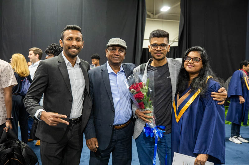 Graduate poses for photo with ceremony guests