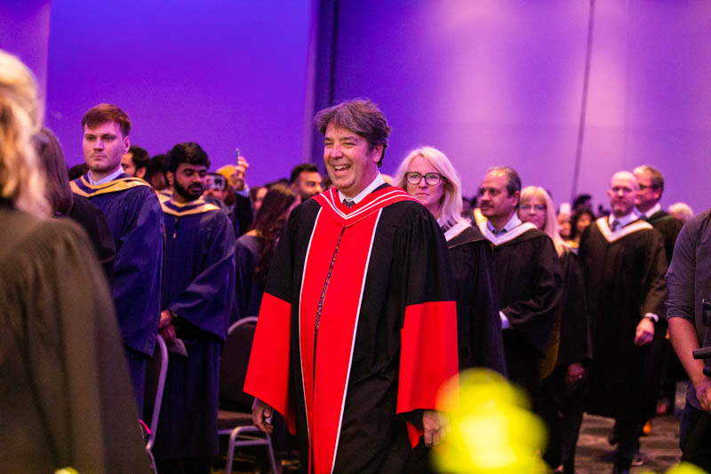Faculty member smiling as they proceed into ceremony hall
