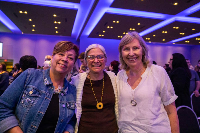 Three ceremony guests take photo together in ceremony hall