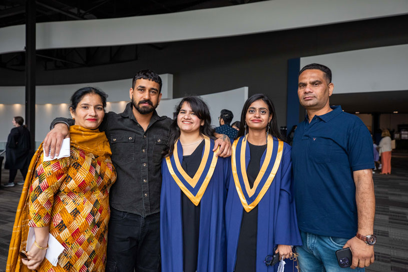 Two graduates take photo with three guests