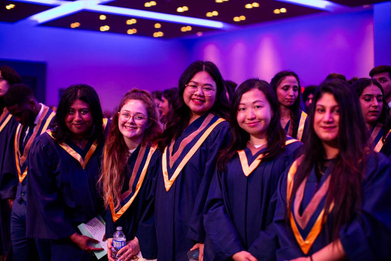 Graduates in ceremony audience smile at camera