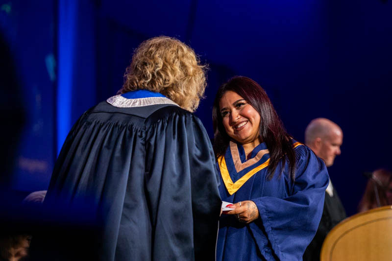 Graduate smiles as they receive certificate