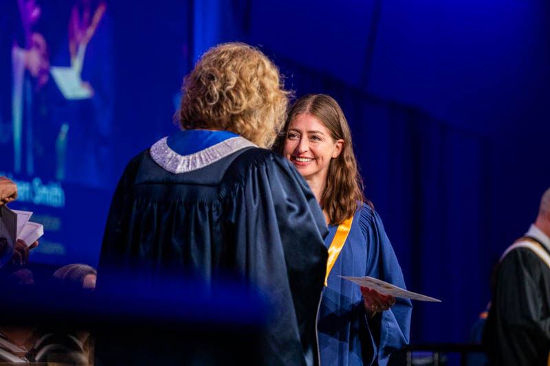 Graduate smiles as they receive certificate