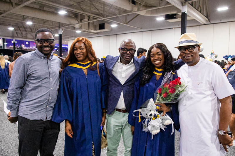 Two graduates take photo with three family members